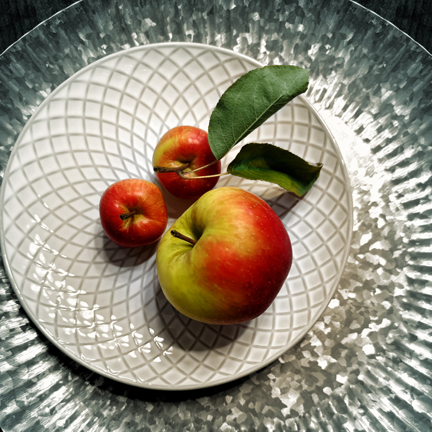 Three apples with plate and platter.
